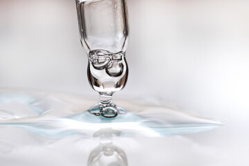 Glass dropper in a drop of cosmetic on a gray background. Concept of making researches in care cosmetics.
