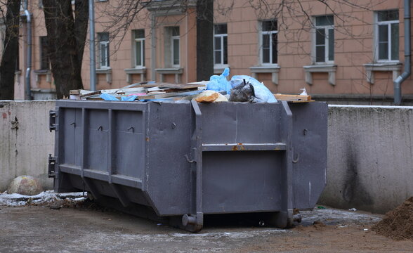 A large gray metal dumpster filled with garbage