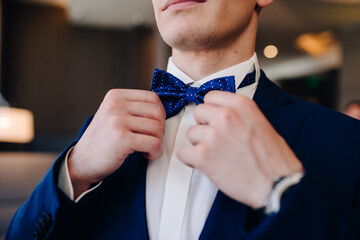 the groom adjusts his bow tie around his neck