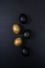 Eggs painted gold and black on dark background. Minimal Easter concept. Golden luxury backdrop