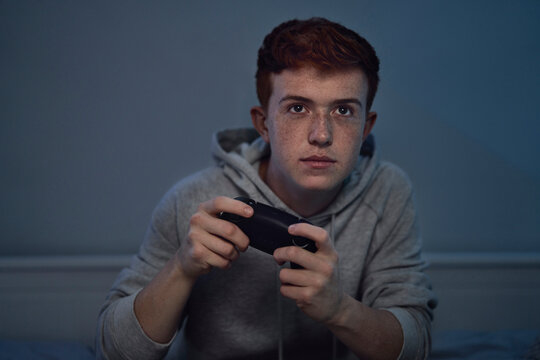 Focus caucasian teenage boy playing on game controller at night