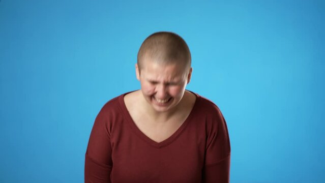 Portrait of smiling laughing gender fluid non binary young woman 20s years old pointing finger posing isolated on blue background studio. People sincere emotions lifestyle concept.