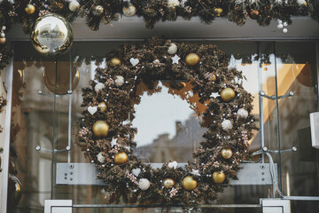 Stylish christmas wreath with silver and gold baubles on building exterior. Modern christmas decor in city street. Winter holidays in Europe. Merry Christmas