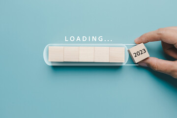 Hand putting wooden cube block for loading progress from 2022 to 2023 to countdown merry christmas...