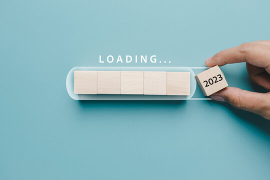 Hand putting wooden cube block for loading progress from 2022 to 2023 to countdown merry christmas and happy new year concept...