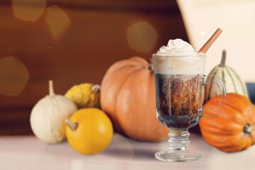 Tasty sweet iced latte with cream in glass with pumpkin.