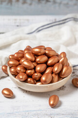 Brown chocolate dragee. Chocolate dragee on a white wood background. close up