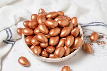 Brown chocolate dragee. Chocolate dragee on a white wood background. close up