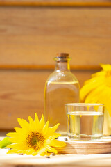 Close-up of sunflower oil in a bottle glass with seeds and sunflower on wooden background
