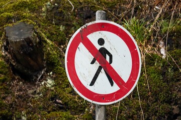 Closeup of a warning sign, forbidding people's entrance on a background of green plants