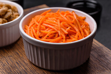 Tasty spicy Korean carrot with spices and herbs on a dark concrete background