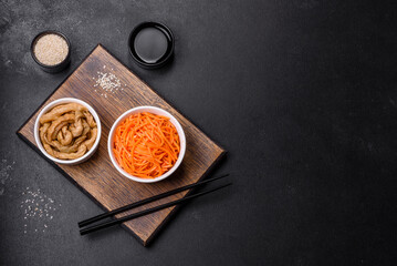 Tasty spicy Korean carrot with spices and herbs on a dark concrete background