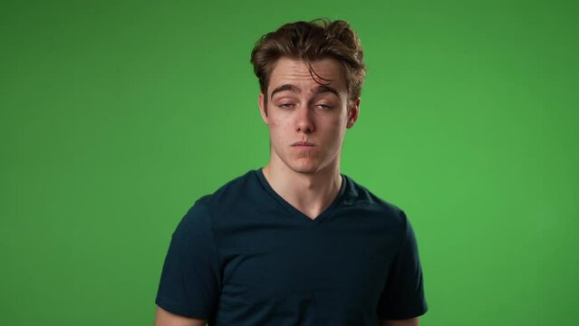 Pointing fingers himself ask say who me waving and smiling, confused young man 20s posing isolated on green screen background in studio. People lifestyle concept. Slow motion