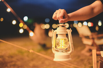 Hand holding a n old lamp, oil lamp or lantern. concept of camping at inght time or campfire...