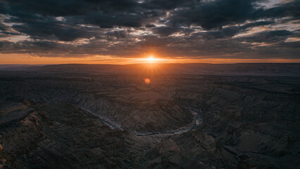 Dramatischer Sonnenuntergang - Blick auf eine Schleife des Fish Rivers bei Sonnenuntergang, wie er sich durch den Fish River Canyon windet (Namibia)