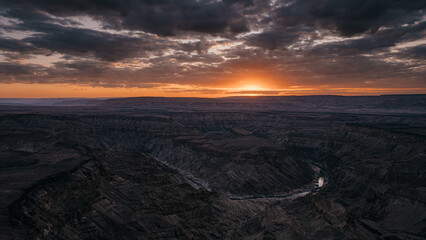 Dramatischer Sonnenuntergang - Blick auf eine Schleife des Fish Rivers bei Sonnenuntergang, wie er sich durch den Fish River Canyon windet (Namibia)