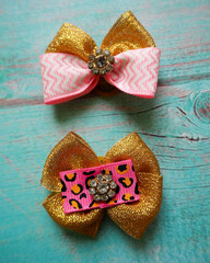 two pink and gold bows lie on a blue wooden table.  view from above.  accessories .  Christmas .  bows for dogs
