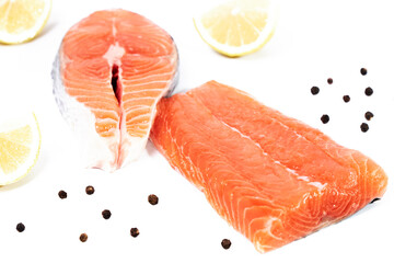 Salmon, fillet and slice of fresh raw fish with lemon slices and black pepper, isolated on white background