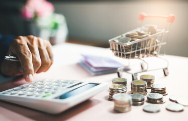 Hand of businessman using calculator to calculate money from savings with stack of coins and coin...