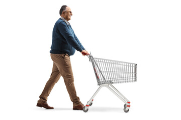 Full length profile shot of a mature man walking and pushing an empty shopping cart