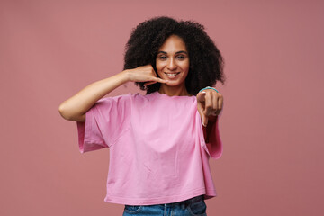 Portrait of young beautiful smiling curly woman doing phone gesture