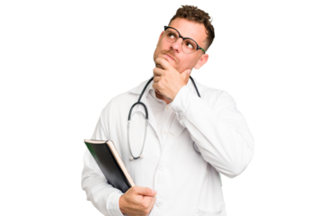 Young doctor caucasian man holding a book isolated looking sideways with doubtful and skeptical expression.
