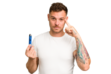 Young caucasian man holding a electronic cigarette isolated pointing temple with finger, thinking, focused on a task.