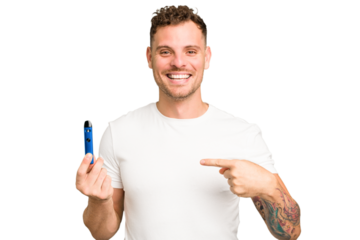Young caucasian man holding a electronic cigarette isolated person pointing by hand to a shirt copy space, proud and confident