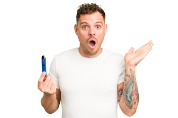 Young caucasian man holding a electronic cigarette isolated surprised and shocked.