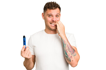 Young caucasian man holding a electronic cigarette isolated biting fingernails, nervous and very anxious.