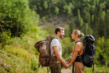 White couple holding hands while hiking in green forest