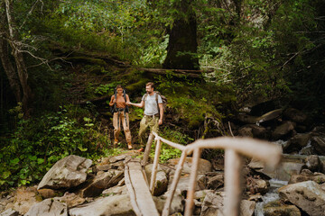 White young couple with backpacks hiking in green forest