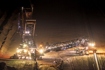 Heavy mining equipment at work in an open-pit mine at dusk.
