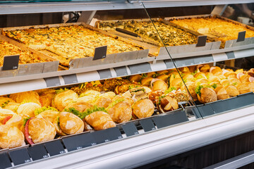 Variety of tasty sandwiches with various fillings in the window of a store or supermarket. Snacks and fast food concept
