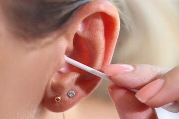 Woman cleaning her ear with cotton swab, people hygiene concept.