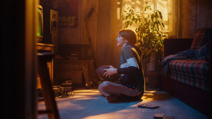 Young Sports Fan Watches American Football Match on TV at Home. Handsome Boy Supporting His Favorite Team. Nervously Playing with Football. Nostalgic Retro Childhood Concept.