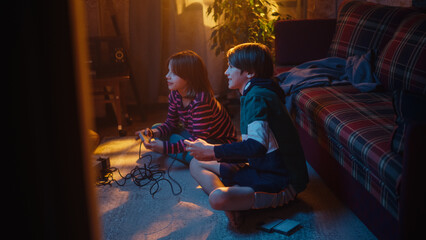 Obraz na płótnie Canvas Nostalgic Childhood Concept. Young Brother and Sister Playing Old-School Arcade Video Game on a Retro TV Set in a Living Room with Period-Correct Interior. Friends Spend the Day at Home Playing Games.