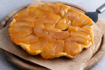 Apple tart tatin on a wooden board on a gray table. The concept of sweet pastries with fruits.