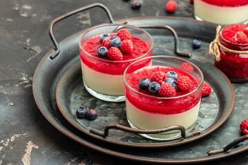 Raspberry Panna cotta with raspberry jelly on a dark background. Berry dessert with cream sauce in small jars. place for text