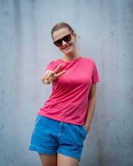 Obraz na płótnie Canvas Female model wearing pink blank t-shirt on the background of an gray wall.