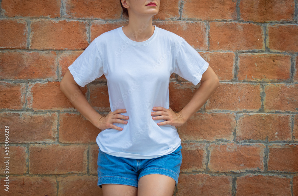 Wall mural Female model wearing white blank t-shirt on the background of an bricks wall.