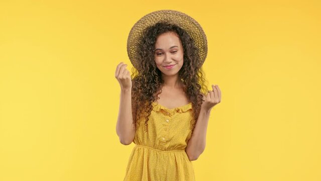 Smiling woman asking money gesture on yellow studio background. Smart summer lady smiles slyly, she has idea how to earn. Profitable investments, stock market game, cryptocurrency mining