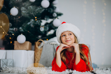 Beautiful girl in santa hat under the christmas tree