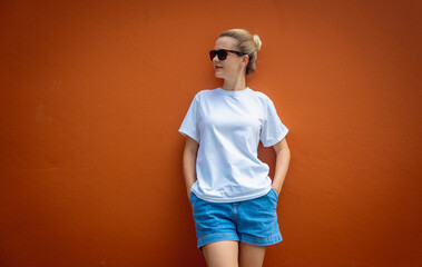 Female model wearing white blank t-shirt on the background of an orange wall.