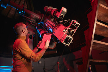Astronomer with a big astronomical telescope in observatory doing science research of space and...
