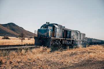 Naklejka premium Ein alter nostalgischer verstaubter Diesel Lok Güterzug fährt durch den Süden von Namibia