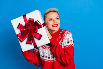 Photo of young satisfied girl happy positive smile shake curious what inside christmas package giftbox dont know isolated on blue color background