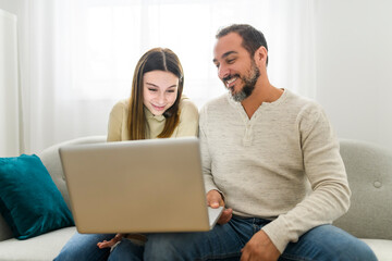 father with teen child daughter having fun using laptop computer at home