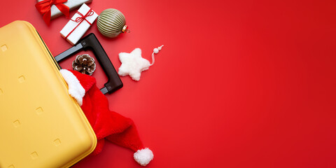 Santa Claus hat lies in yellow suitcase, christmas baubles and gifts on red background. Concept:...