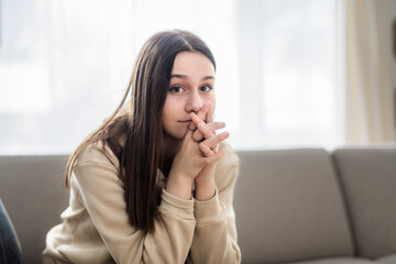 teen sitting on couch at home Frustrated confused female feels unhappy problem in personal life